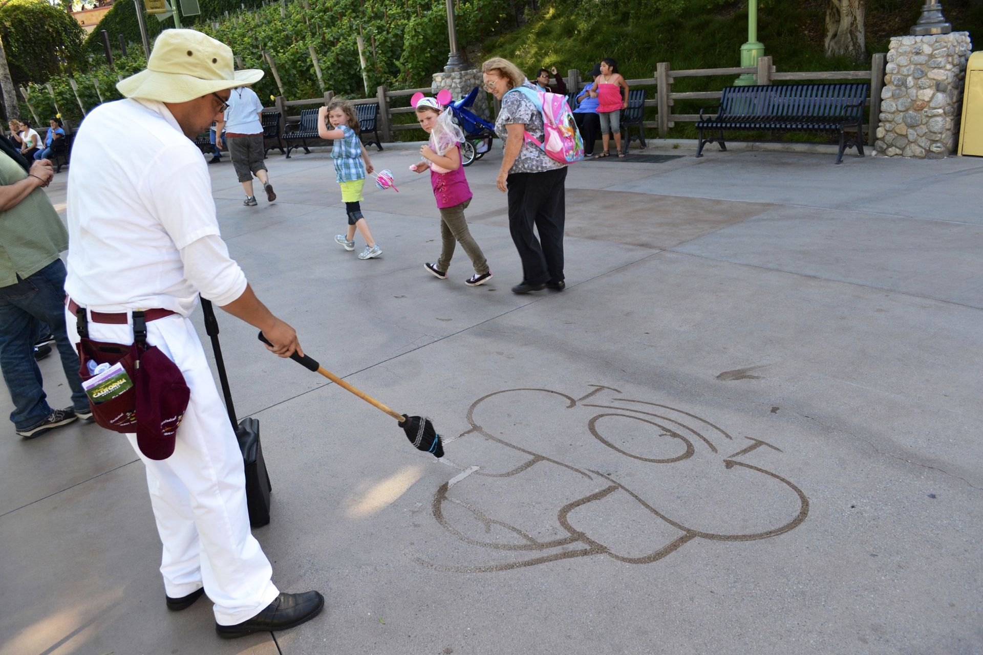 Custodial staff member drawing a Disney character with a mop
