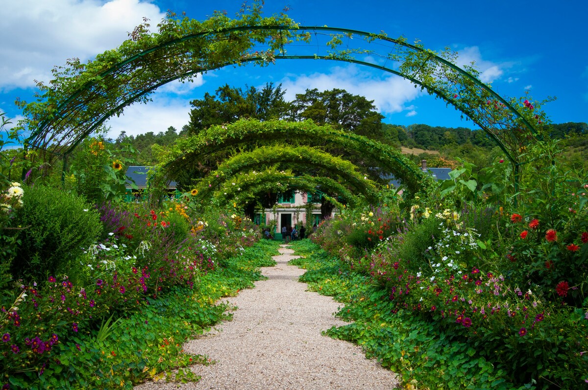 Pathway lined with colorful flowers leads under arched green trellises toward a house, against a backdrop of lush trees and bright blue sky. Photo by [Veronica Reverse](https://unsplash.com/@vereverse?utm_source=unsplash&utm_medium=referral&utm_content=creditCopyText) on [Unsplash](https://unsplash.com/photos/single-perspective-of-pathway-leading-to-house-qYwyRF9u-uo?utm_source=unsplash&utm_medium=referral&utm_content=creditCopyText)